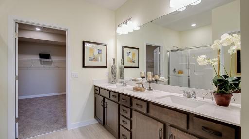 Large primary en suite with double vanity, quartz countertops, linen closet and private water closet. Second walk-in closet is off the primary bathroom. Model photo. Options and colors will vary. See listing agent for home specific selections.