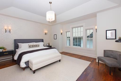 The tray ceiling and beautiful wall sconces elevate ambiance in the primary bedroom!