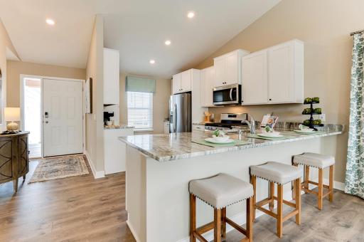 Just steps from either entry door to carry in groceries and ample counter and storage space as well. Stainless appliances, quartz counters, and tile backsplash included. *Photo is of a previous model home. Colors and selections shown will vary.