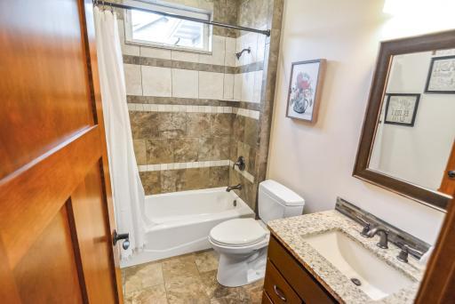 Full main floor bath adjacent to bedroom/office with tile walls and floor, built-in vanity.