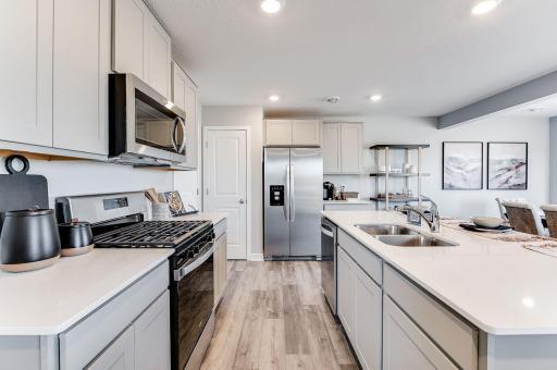 Gorgeous stone grey cabinets with quartz countertops, beautiful stainless appliances and vented micro-hood to the outside. (Model photo, colors may vary.)