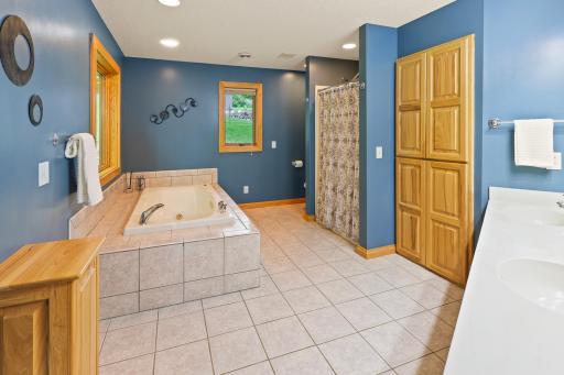 Lots of storage in this primary full bath. Separate walk-in shower and jetted tub. It also has a clothes shoot to the laundry room!