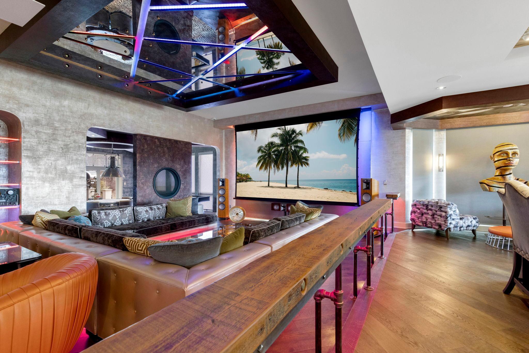 The spacious and open concept living room overlooks the stunning property or the theater style, drop-down projection screen.