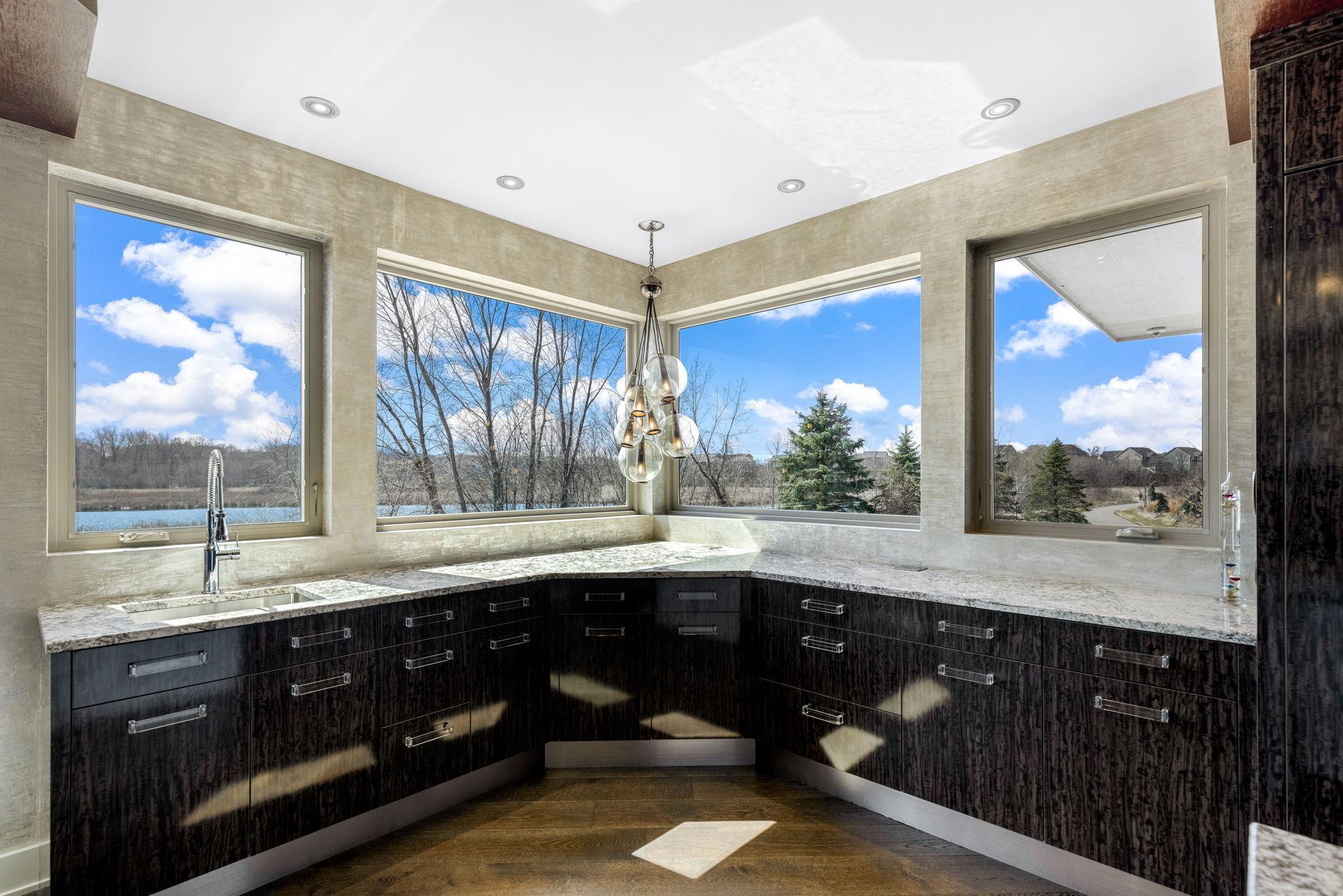 A stunning chef’s kitchen features wall to wall windows, 2 built-in refrigerators, 2 sinks,
a center island range with a ceiling mounted, recessed range hood, double oven, abundant granite
countertop space including a massive center island.