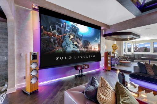 The spacious and open concept living room overlooks the stunning property or the theater style, drop-down projection screen.
