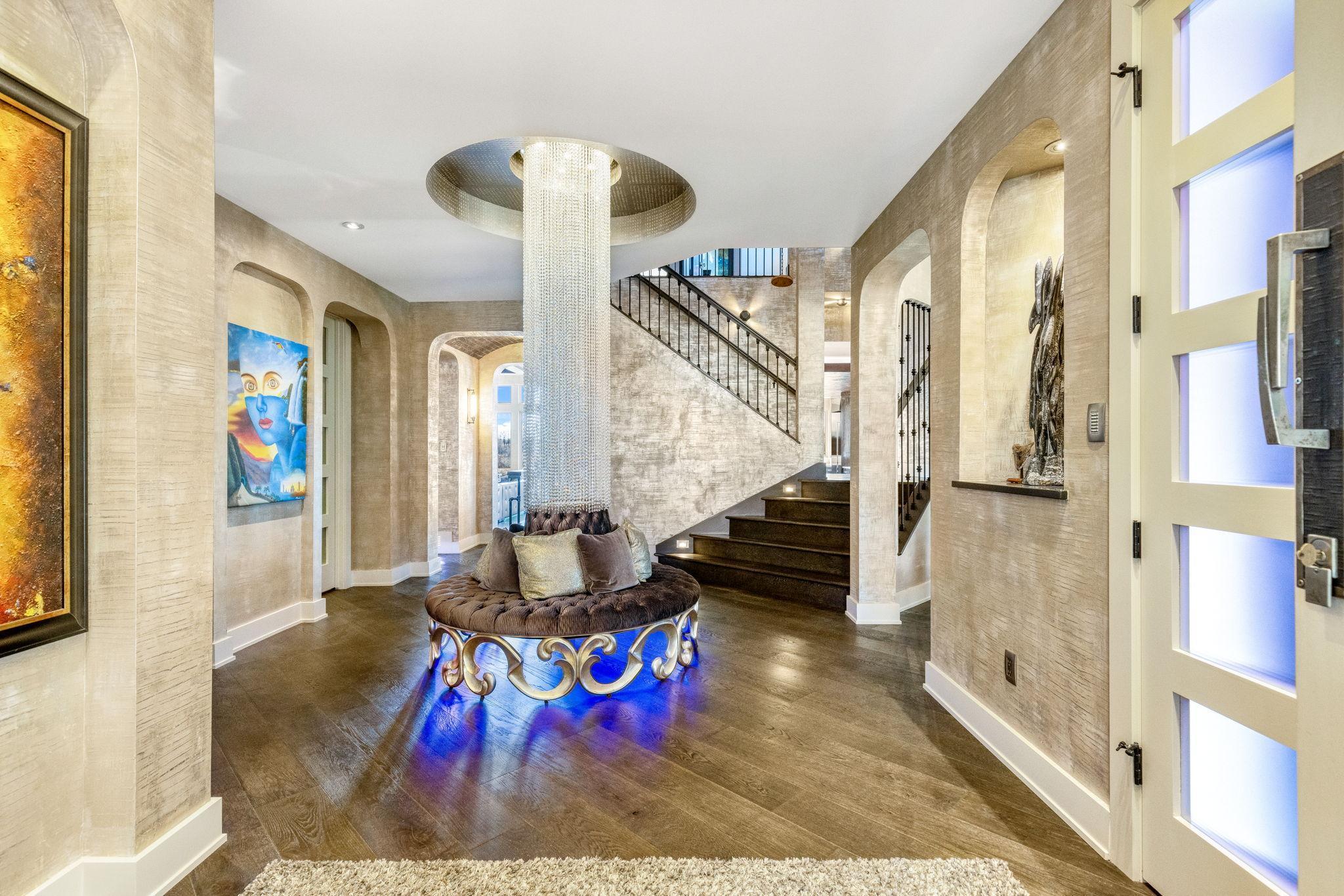 The large grand foyer features a stunning crystal centerpiece and surrounding circular bench.