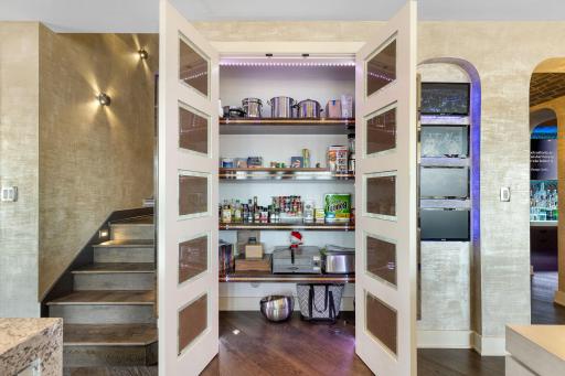 The generous kitchen pantry features accent lighting through frosted glass windows.