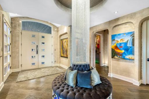The large grand foyer features a stunning crystal centerpiece and surrounding circular bench.