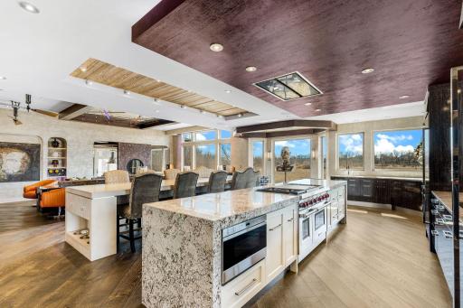 A stunning chefâs kitchen features wall to wall windows, 2 built-in refrigerators, 2 sinks,
a center island range with a ceiling mounted, recessed range hood, double oven, abundant granite
countertop space including a massive center island.