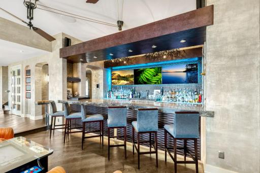The full sized bar offers abundant storage, a fridge with wine storage, a turn-table set-up, and a martini
shaped bar sink. The floor height behind the bar puts the countertop at counter level, while the seated sided of the bar is at bar top level.