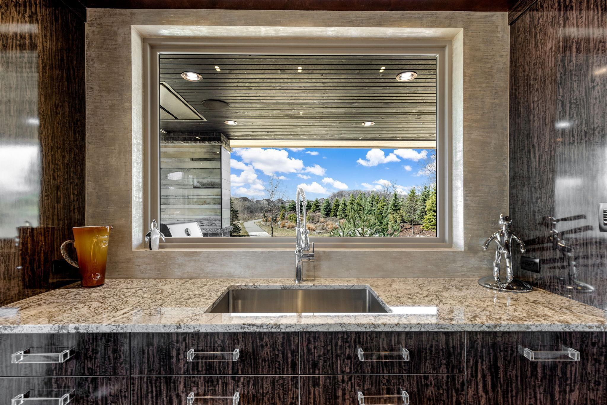 A stunning chef’s kitchen features wall to wall windows, 2 built-in refrigerators, 2 sinks,
a center island range with a ceiling mounted, recessed range hood, double oven, abundant granite
countertop space including a massive center island.