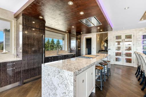 A stunning chef’s kitchen features wall to wall windows, 2 built-in refrigerators, 2 sinks,
a center island range with a ceiling mounted, recessed range hood, double oven, abundant granite
countertop space including a massive center island.