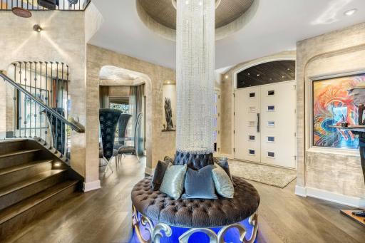 The large grand foyer features a stunning crystal centerpiece and surrounding circular bench.
