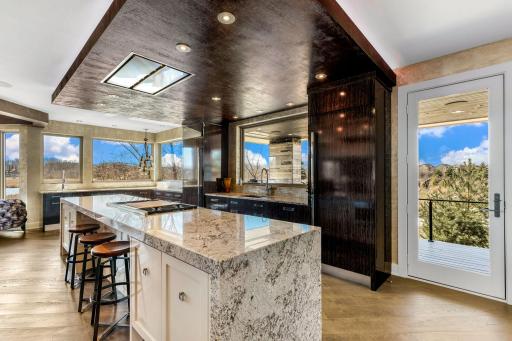 A stunning chefâs kitchen features wall to wall windows, 2 built-in refrigerators, 2 sinks,
a center island range with a ceiling mounted, recessed range hood, double oven, abundant granite
countertop space including a massive center island.