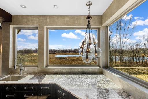 A stunning chefâs kitchen features wall to wall windows, 2 built-in refrigerators, 2 sinks,
a center island range with a ceiling mounted, recessed range hood, double oven, abundant granite
countertop space including a massive center island.