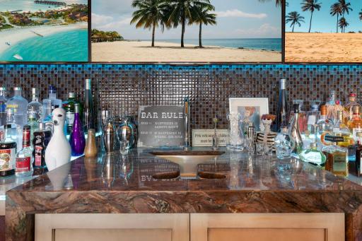 The full sized bar offers abundant storage, a fridge with wine storage, a turn-table set-up, and a martini
shaped bar sink. The floor height behind the bar puts the countertop at counter level, while the seated sided of the bar is at bar top level.