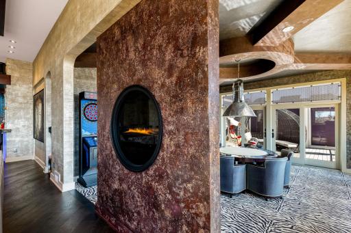 A unique 2-sided circular, gas fireplace joins the game room and living room space.