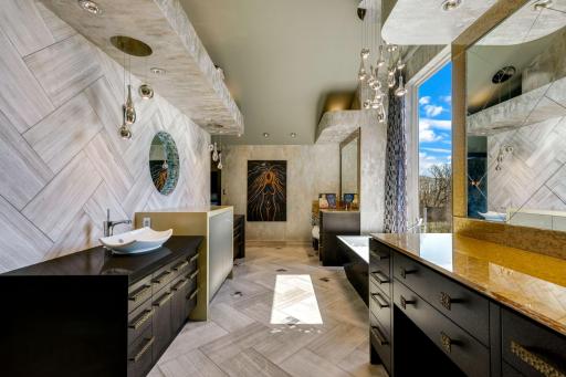 The bright and open primary bathroom offers a massive 2-person shower, 2 separate, commode rooms with custom toilets, extensive Corian countertop vanity space and a large soaking tub with private views