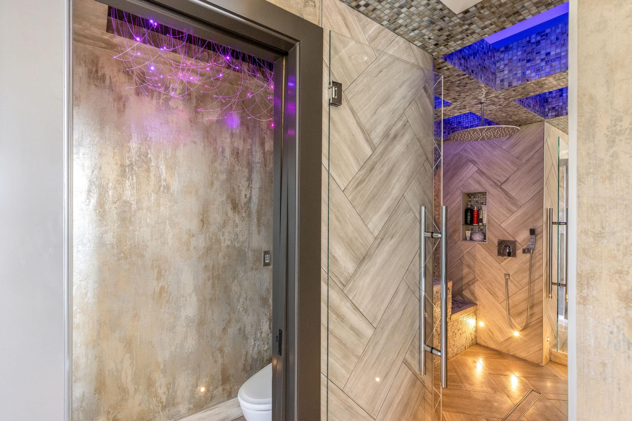 The bright and open primary bathroom offers a massive 2-person shower, 2 separate, commode rooms with custom toilets, extensive Corian countertop vanity space and a large soaking tub with private views