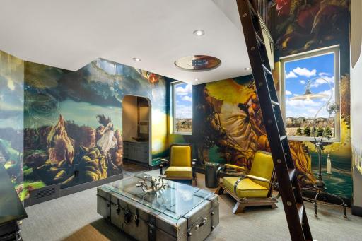 This one of a kind bedroom features a cozy loft bed, movie watching nook and stunning wall art.