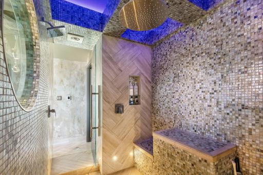 The bright and open primary bathroom offers a massive 2-person shower, 2 separate, commode rooms with custom toilets, extensive Corian countertop vanity space and a large soaking tub with private views