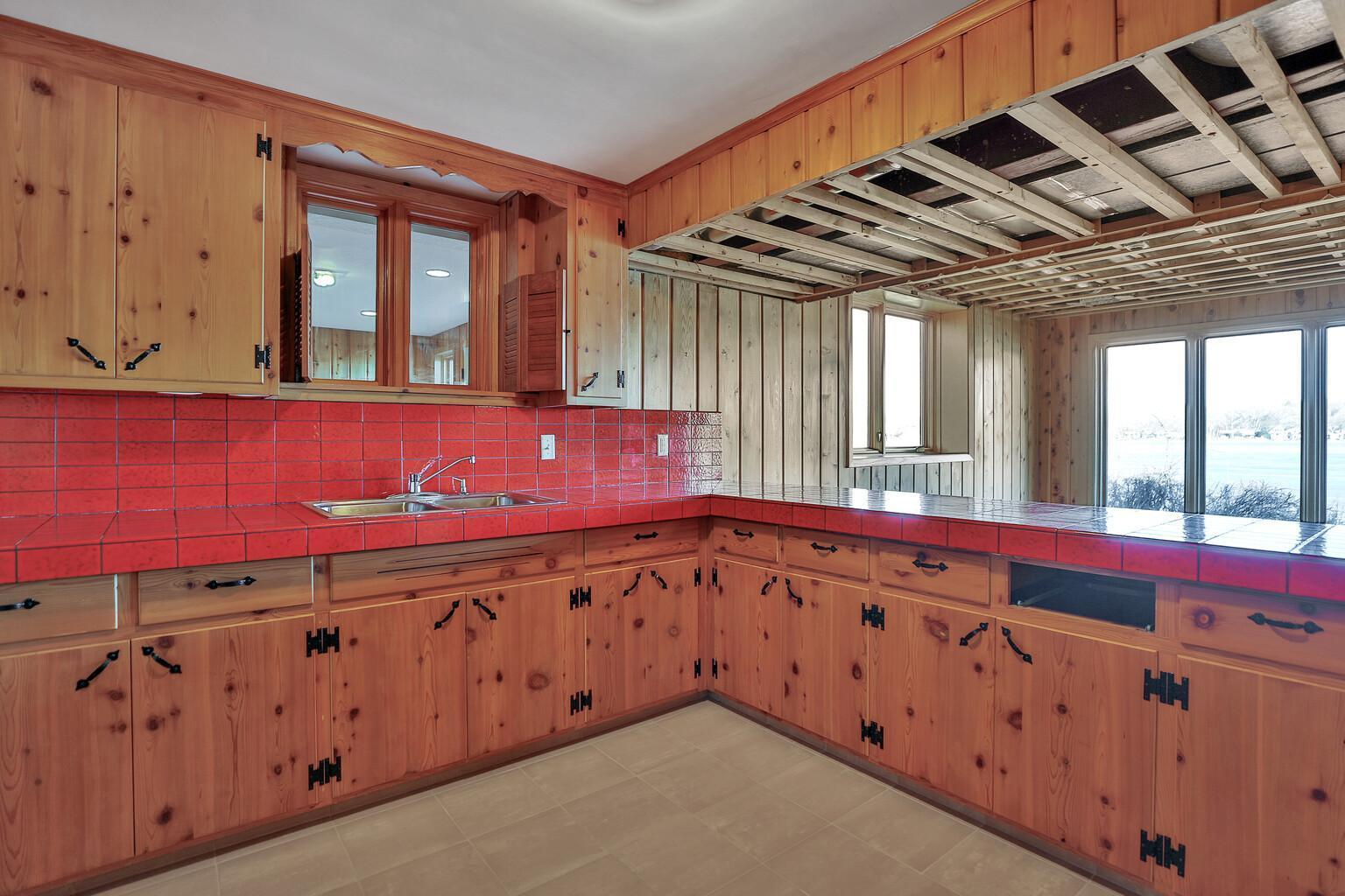 Knotty pine cabinetry. Recent addition can be seen through the windows above the sink.