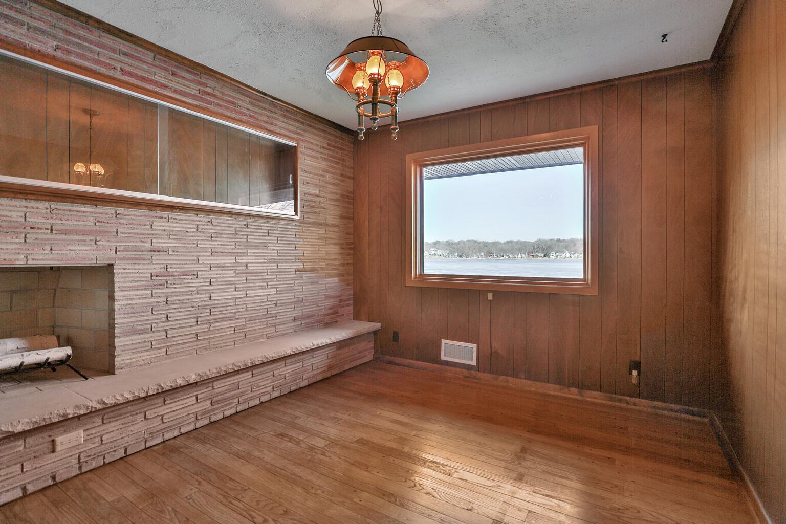 Main floor Den/Office at lake side with built in book shelves and stone fireplace.