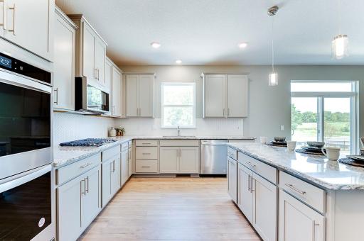 The kitchen of your dreams - complete with stunning Quartz countertops, elegant backsplash, modern cabinetry & a stainless steel appliances that'll leave the family chef in their happy place! Photo of model home, color & options will vary.