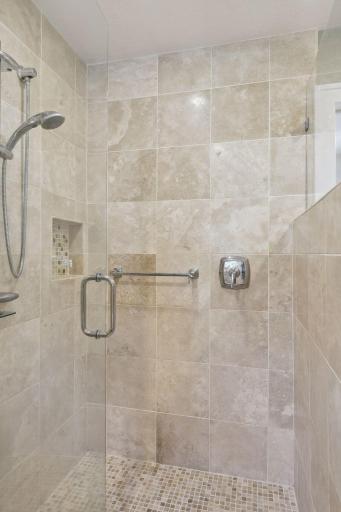 The large shower all finished in stone with custom glass doors.