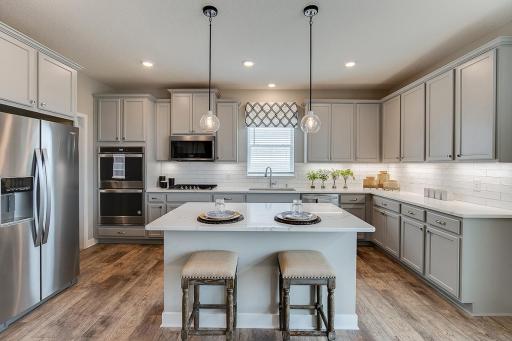 The center of the kitchen, the island will have Quartz countertops and can serve as a perfect gathering piece for both family night, and for entertaining your guests. Photo of model home, color and options will vary.