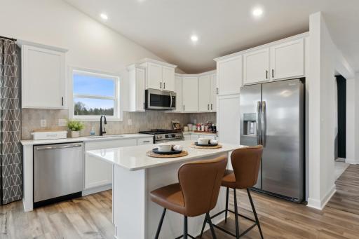The kitchen is home to a large center island complete with granite countertops, stainless appliances, and a luxurious gas cooktop.