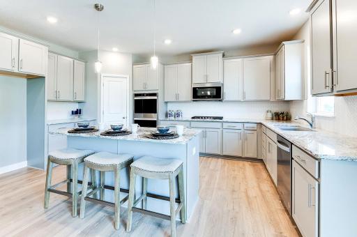 Large kitchen island, corner pantry, signature appliance package, white cabinets (not shown), quartz counters and ceramic backsplash make this kitchen a dream! Model photo. Options and colors will vary.