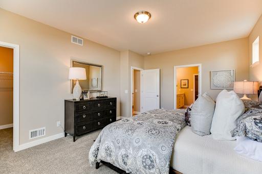 Enjoy starting your day in the comfort of your beautiful primary suite. Located just off the living room, this primary suite makes main level living easy. Photo shows access to first walk in closet and the primary bath *Photo of previous model.