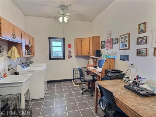 The laundry room is complete with tile floors, many cabinets, ceiling fan, washer & dryer and utility sink.