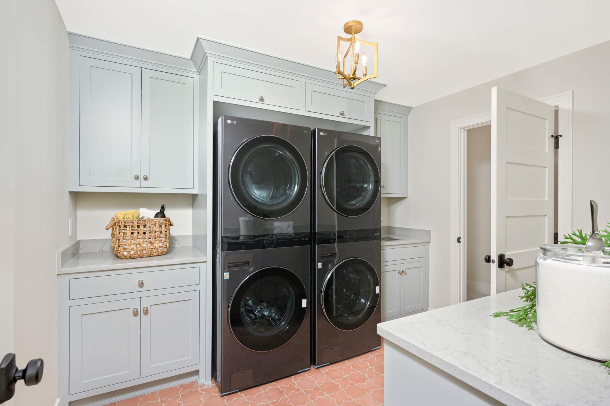 The laundry room has custom cabinetry along with a double stacked washer and dryer