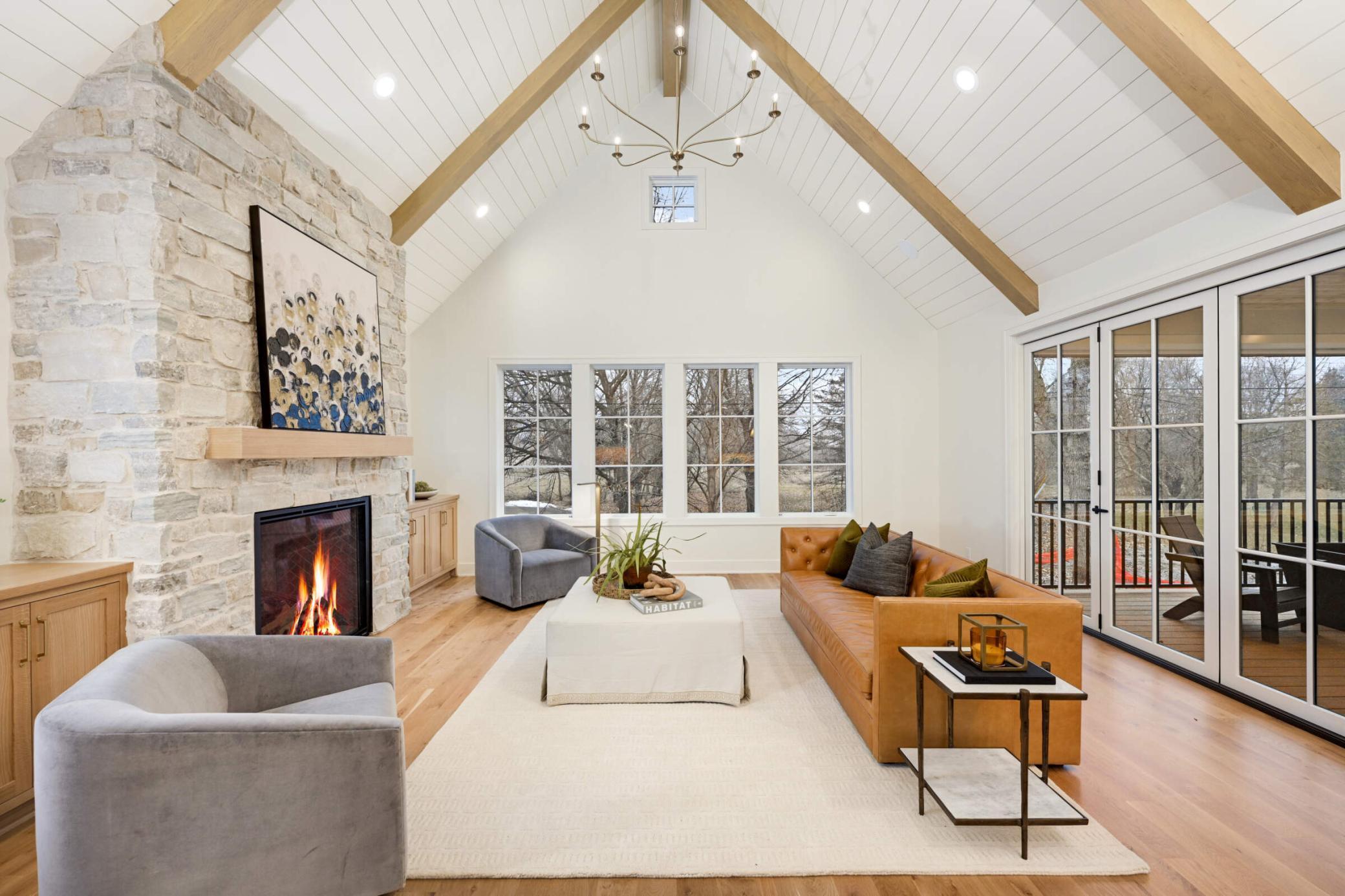 Large vaulted great room with large fireplace and three panel, accordion door leading onto the screened-in porch