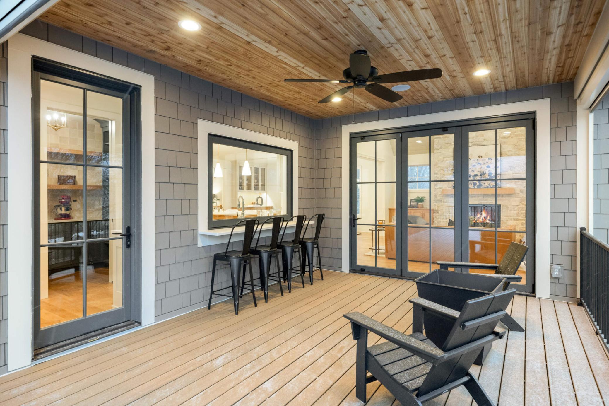 Screened in porch with serving bar. The window in front of the chairs completely opens to stay connected with guests while working in the kitchen.