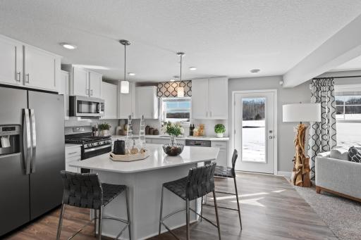 The Jefferson Home provides an open and bright modern kitchen and is anchored by a large center island and is surrounded by expansive countertops providing true eat in capabilities. Photo is of a previously built home, colors and finishes may vary.