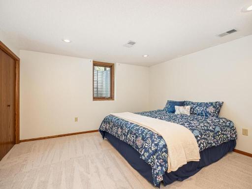 Fourth bedroom in the basement with plush carpeting and egress window, perfect for guests.