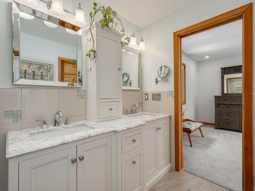 Double vanity in primary suite with marble countertops, great lighting, and plenty of storage.