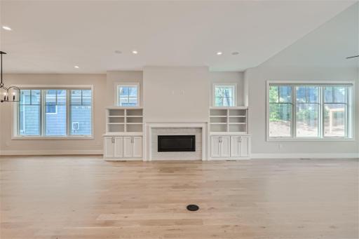 Remarkable white oak 5" wood flooring and sleek fireplace in the main level great room. (Picture of a previously built home.)