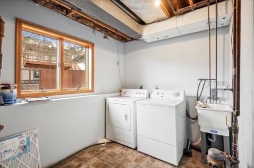 Laundry and mechanical room with room for storage and a utility sink with large windows to the backyard