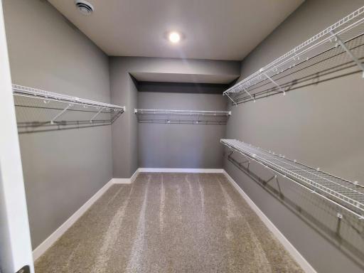 View of larger primary walk-in closet. Photo of actual home.