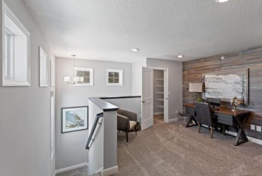 The upper level features a cozy loft for extra space, along with a storage closet. Use as another family gathering area, TV room, or home office. (Photo of decorated model, actual home's finishes may vary slightly)