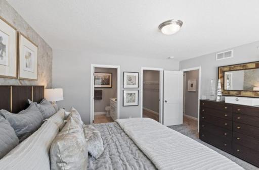Spacious owner's suite with large windows, a walk-in closet, and private bathroom. (Photo of decorated model, actual home's finishes may vary slightly)