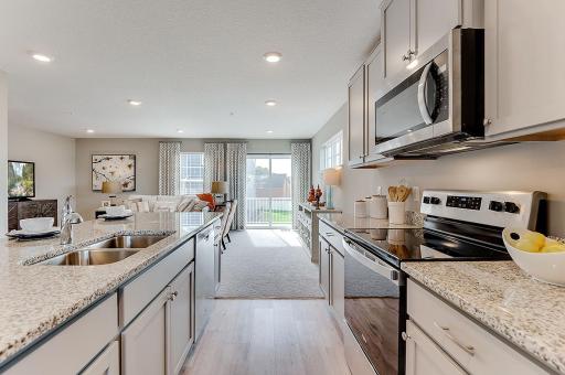 Stainless appliances (gas range) and a vented microwave fan round out this gorgeous kitchen and are sure to make your friends jealous! Model home, details will vary.