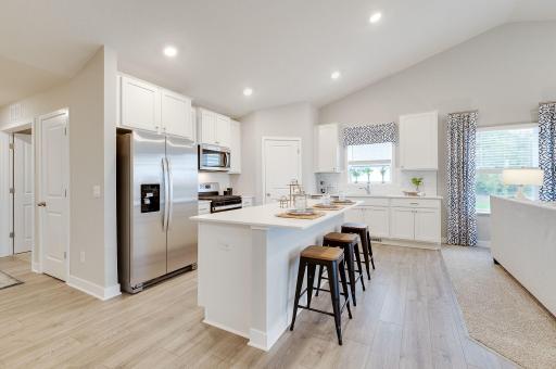 A spacious center island covered in quartz! Don't miss the walk-in pantry and oversized subway tiled backsplash. *Photo of previous model home. Colors and selections may vary from what is shown.