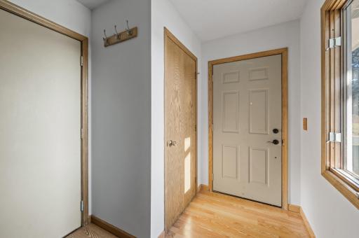 The spacious foyer features a convenient coat closet, wood flooring, and a window for natural light.
