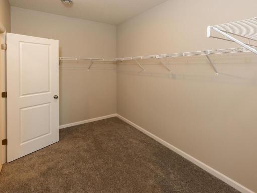 Primary Suite Walk In Closet. Photo taken of another home with similar plan and finishes. Photos and renderings may not depict actual plan, materials, & finishes may vary. All measurements are approximate.
