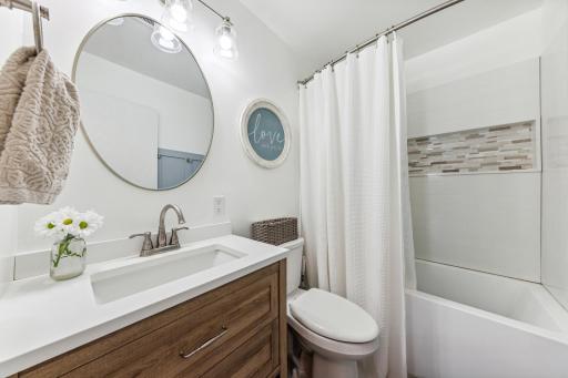 Dazzling remodeled main level bathroom with new vanity, tile floors, deep soak tub, and large niche.